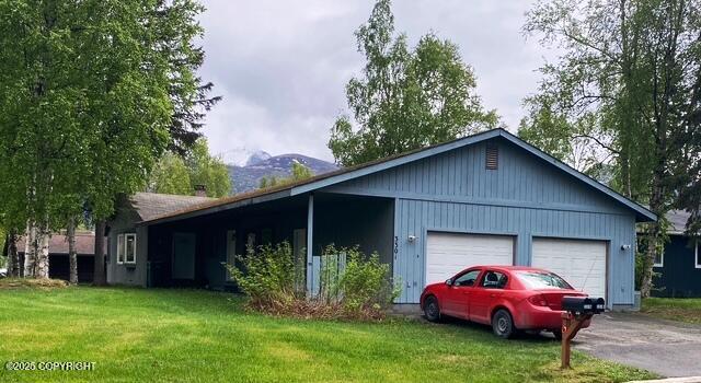 3301 Pussywillow St, Anchorage, AK 99504 - view of side of home featuring an attached garage, a lawn, and asphalt driveway