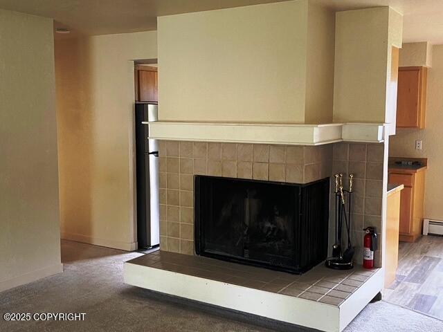 3301 Pussywillow St, Anchorage, AK 99504 - detailed view of a tiled fireplace, a fire extinguisher, baseboards, freestanding refrigerator, and a baseboard heating unit