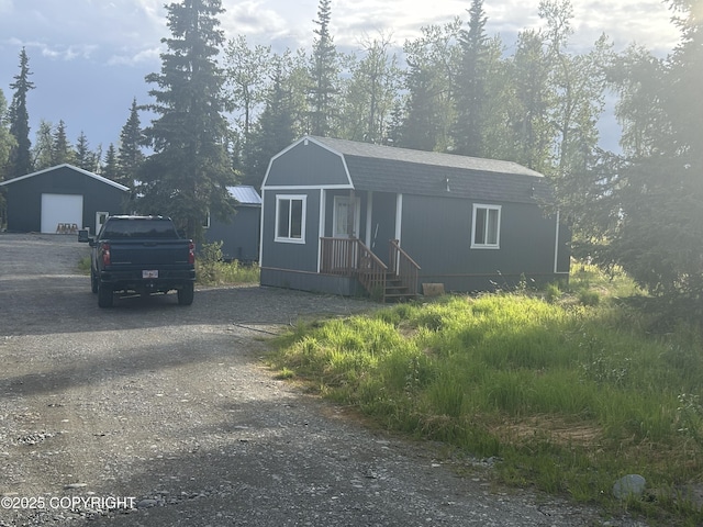 17185 Lunchbox Dr, Ninilchik, AK 99639 - view of front of house with a gambrel roof, dirt driveway, a garage, an outdoor structure, and roof with shingles