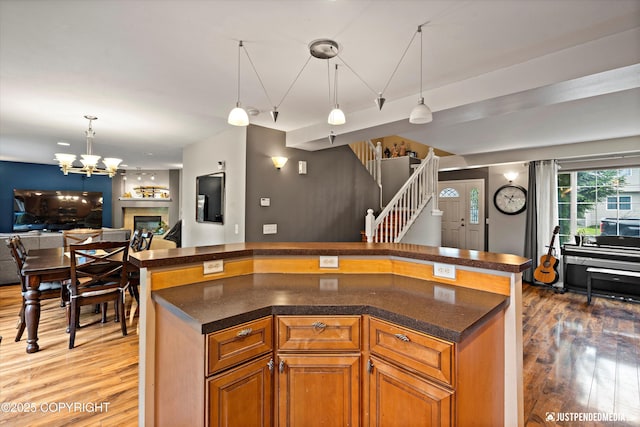1503 N Heather Meadows Loop Unit 54, Anchorage, AK 99507 - kitchen with open floor plan, light wood-type flooring, a chandelier, brown cabinetry, and pendant lighting
