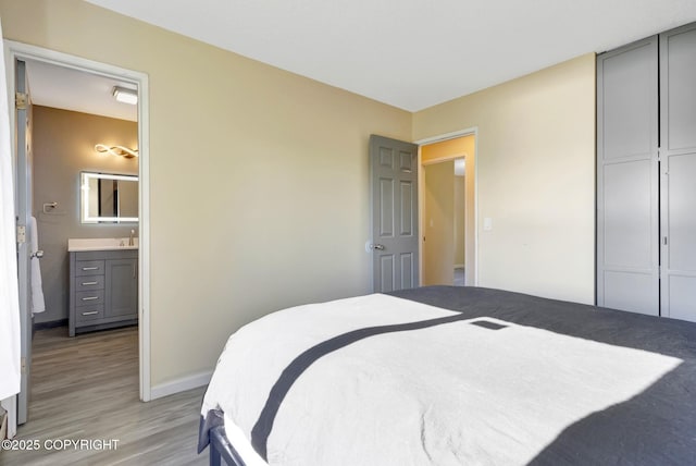 4665 Cascade Cir, Anchorage, AK 99502 - bedroom featuring light wood-style flooring, baseboards, ensuite bathroom, a sink, and a closet