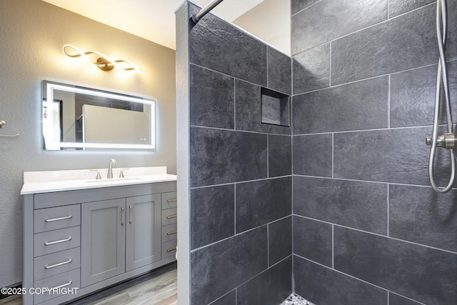 4665 Cascade Cir, Anchorage, AK 99502 - bathroom featuring tiled shower, vanity, and wood finished floors