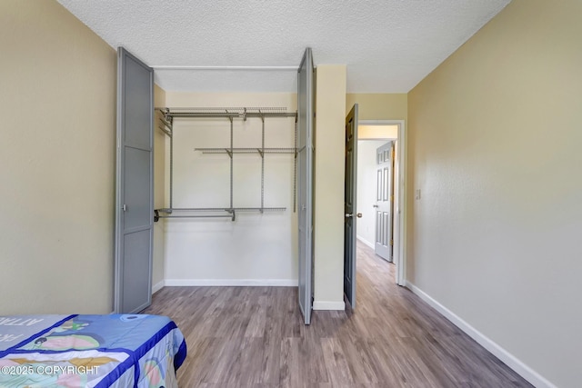 4665 Cascade Cir, Anchorage, AK 99502 - bedroom featuring wood finished floors, a closet, baseboards, and a textured ceiling