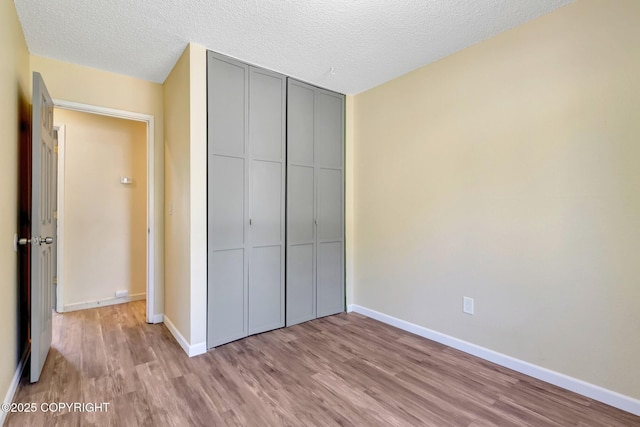 4665 Cascade Cir, Anchorage, AK 99502 - unfurnished bedroom with wood finished floors, a closet, baseboards, and a textured ceiling