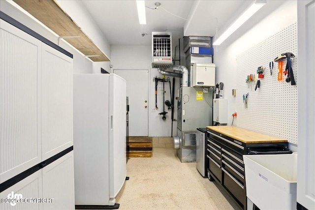 10410 Constitution St, Anchorage, AK 99515 - basement with freestanding refrigerator, a heating unit, and a workshop area