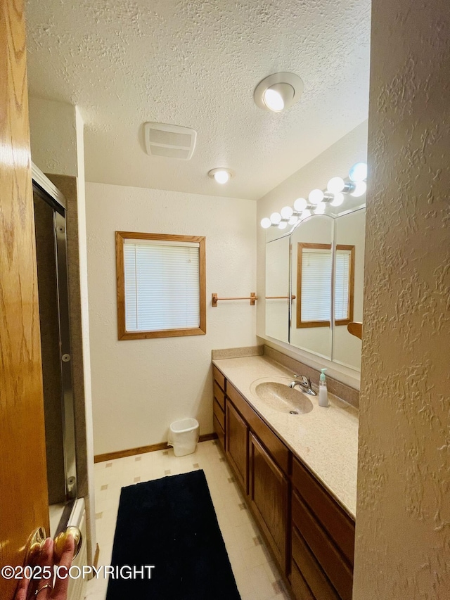 1310 Madsen Ave, Kodiak, AK 99615 - bathroom with a textured ceiling, a shower with door, vanity, a textured wall, and tile patterned floors
