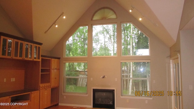 2024 Oxbow Cir, Anchorage, AK 99516 - unfurnished living room with high vaulted ceiling, track lighting, plenty of natural light, and a glass covered fireplace