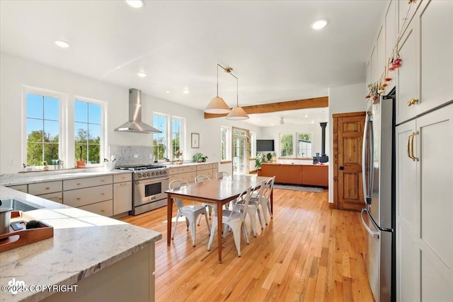 7350 E Narnia Cir, Palmer, AK 99645 - kitchen with stainless steel appliances, wall chimney range hood, light wood finished floors, open floor plan, and light stone counters