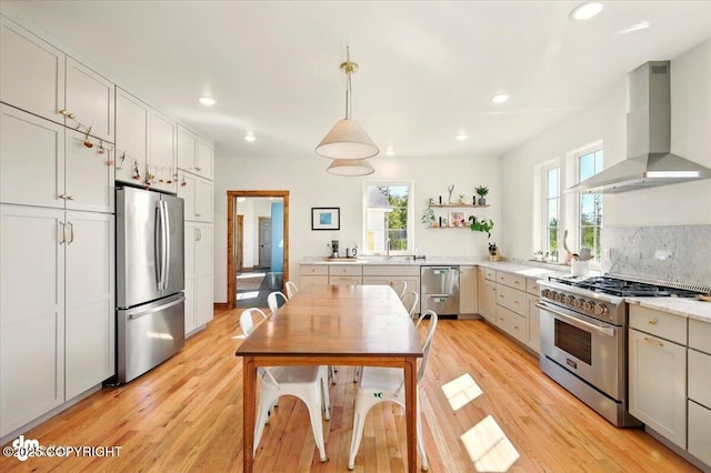 7350 E Narnia Cir, Palmer, AK 99645 - kitchen featuring stainless steel appliances, wall chimney exhaust hood, light wood-style flooring, light countertops, and recessed lighting
