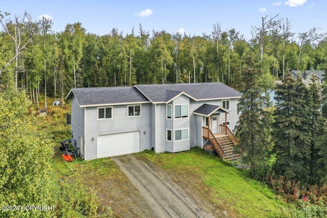 7879 W Sally Ct, Wasilla, AK 99623 - traditional-style house featuring driveway, a view of trees, an attached garage, and a shingled roof