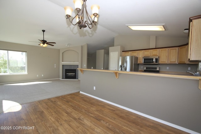 1932 Casey Cusack Loop, Anchorage, AK 99515 - kitchen featuring stainless steel appliances, vaulted ceiling, a ceiling fan, a peninsula, and a tiled fireplace