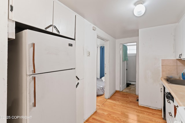 241 N Flower St, Anchorage, AK 99508 - kitchen with freestanding refrigerator, white cabinets, light wood finished floors, light countertops, and baseboard heating