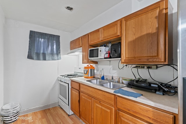 241 N Flower St, Anchorage, AK 99508 - kitchen featuring white appliances, a sink, under cabinet range hood, light countertops, and light wood-type flooring