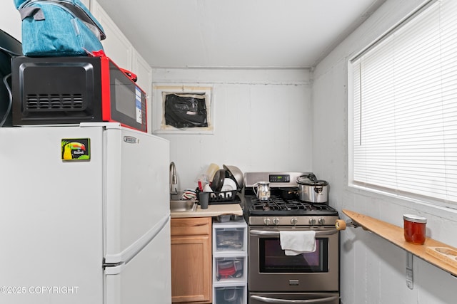 241 N Flower St, Anchorage, AK 99508 - kitchen featuring freestanding refrigerator, stainless steel gas range, light countertops, and a sink
