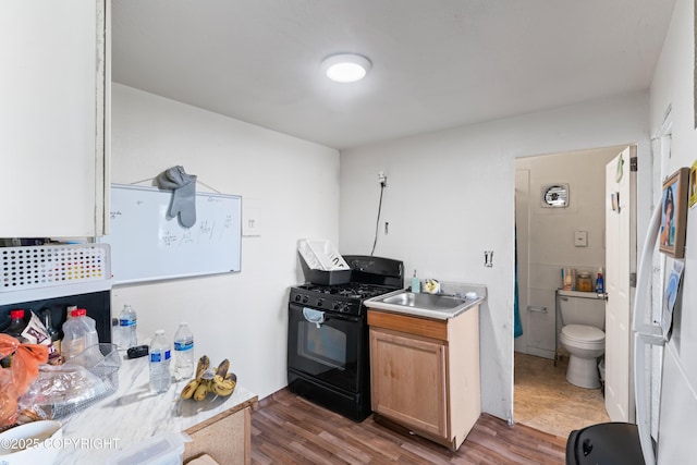241 N Flower St, Anchorage, AK 99508 - kitchen featuring black range with gas stovetop, wood finished floors, light countertops, and a sink