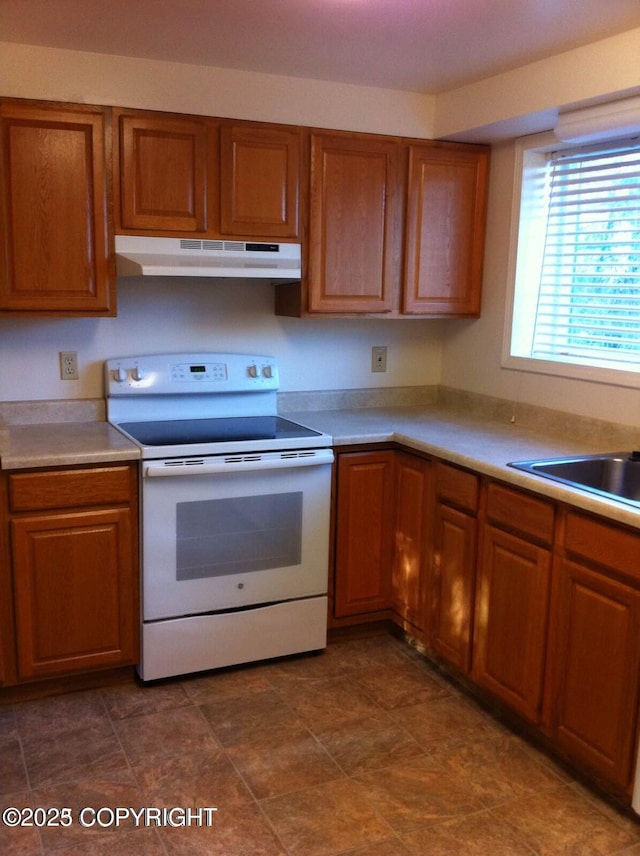 4312 Penguin St, Anchorage, AK 99503 - kitchen featuring white range with electric stovetop, under cabinet range hood, and brown cabinets
