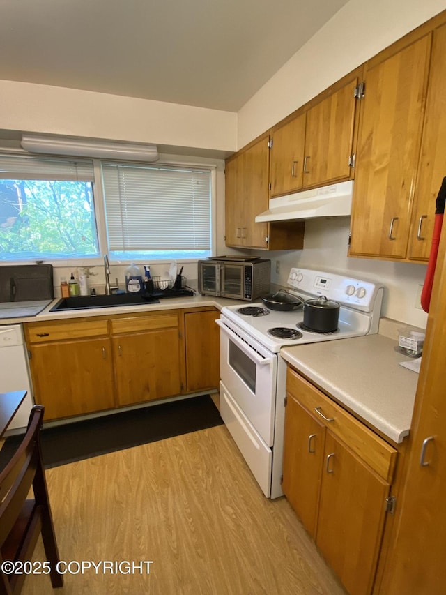 4312 Penguin St, Anchorage, AK 99503 - kitchen featuring electric stove, under cabinet range hood, a sink, light countertops, and brown cabinets