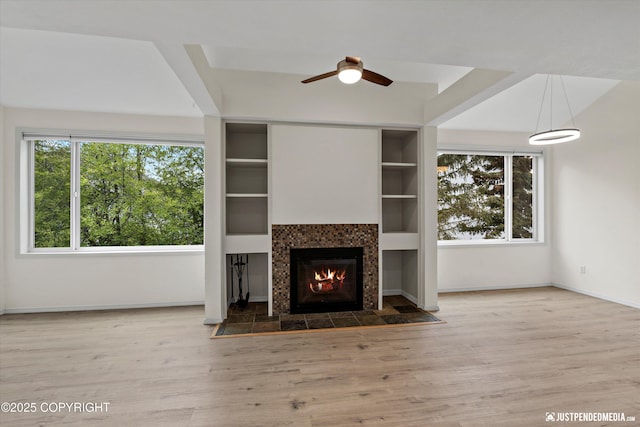 905 Wild Rose Ct # 905, Anchorage, AK 99518 - unfurnished living room featuring plenty of natural light, a tiled fireplace, a ceiling fan, and wood finished floors