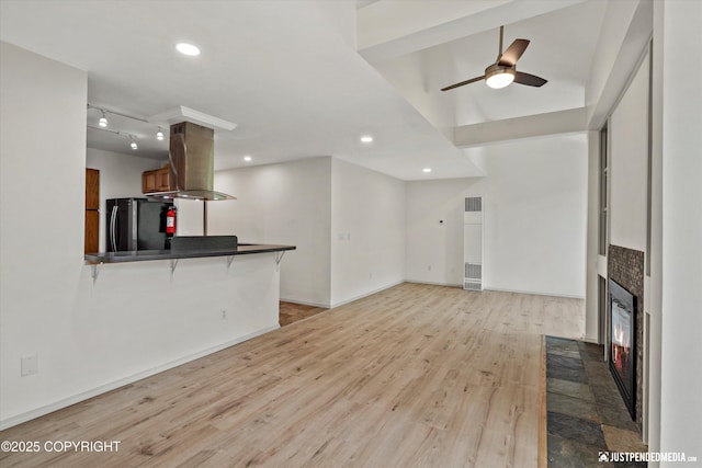 905 Wild Rose Ct # 905, Anchorage, AK 99518 - unfurnished living room featuring a heating unit, a fireplace with flush hearth, light wood-style flooring, a ceiling fan, and recessed lighting