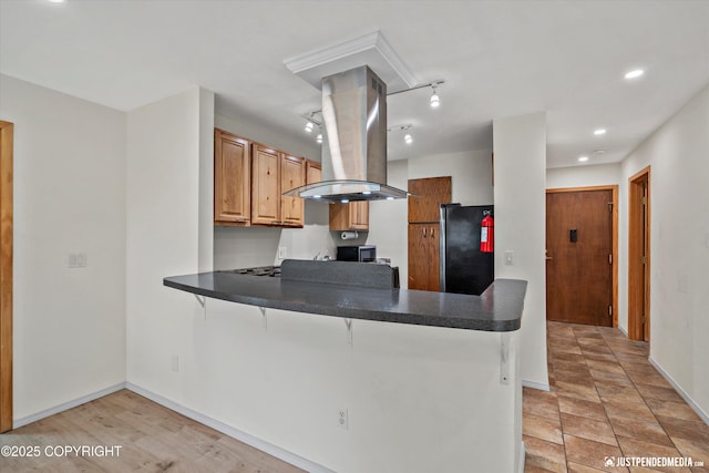 905 Wild Rose Ct # 905, Anchorage, AK 99518 - kitchen with island exhaust hood, freestanding refrigerator, a peninsula, a kitchen breakfast bar, and dark countertops