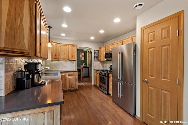 1061 E Mulchatna Dr, Wasilla, AK 99654 - kitchen with stainless steel appliances, arched walkways, dark countertops, decorative backsplash, and dark wood-style floors
