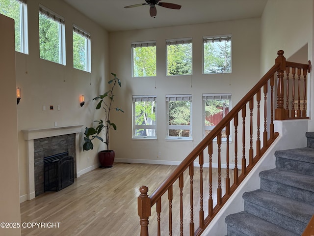 13125 W Curry Ridge Cir, Eagle River, AK 99577 - staircase with a high ceiling, ceiling fan, wood finished floors, a stone fireplace, and baseboards