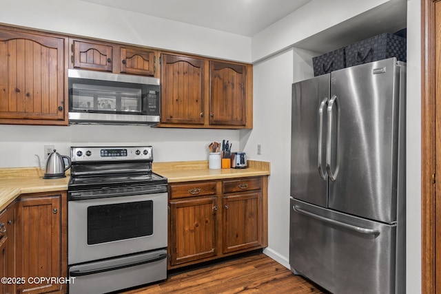 45035 Ptarmigan Pl, Soldotna, AK 99669 - kitchen featuring stainless steel appliances, light countertops, dark wood-type flooring, and brown cabinets