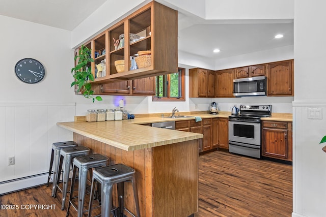 45035 Ptarmigan Pl, Soldotna, AK 99669 - kitchen with stainless steel appliances, a peninsula, dark wood-style floors, light countertops, and a breakfast bar