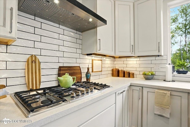 8727 Turlock Dr, Eagle River, AK 99577 - kitchen featuring wall chimney exhaust hood, stainless steel gas stovetop, tasteful backsplash, and white cabinets