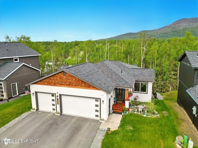 8727 Turlock Dr, Eagle River, AK 99577 - ranch-style house with a view of trees, driveway, an attached garage, a mountain view, and a front lawn