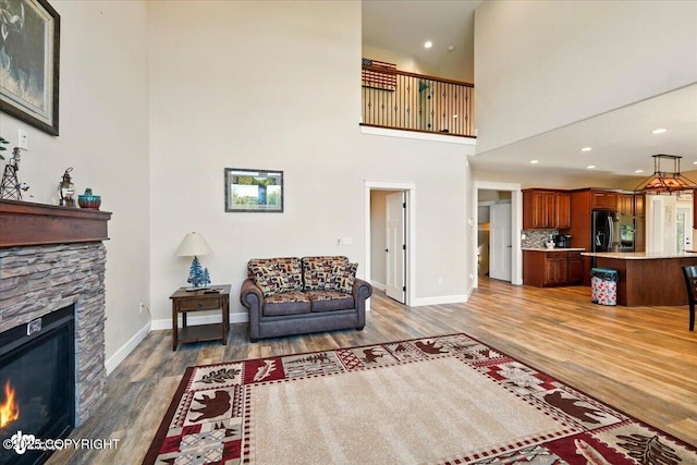 2034 E Sage Rd, Wasilla, AK 99654 - living area featuring wood finished floors, a stone fireplace, baseboards, a towering ceiling, and recessed lighting