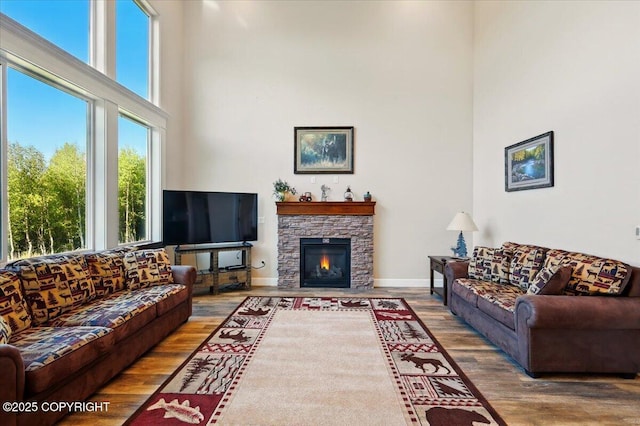 2034 E Sage Rd, Wasilla, AK 99654 - living room with wood finished floors, a towering ceiling, a stone fireplace, and baseboards