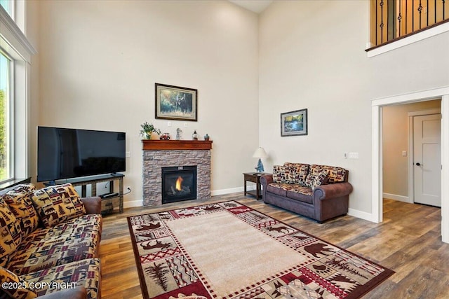 2034 E Sage Rd, Wasilla, AK 99654 - living room featuring a towering ceiling, wood finished floors, baseboards, and a stone fireplace