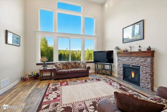 2034 E Sage Rd, Wasilla, AK 99654 - living room with wood finished floors, a stone fireplace, a high ceiling, and baseboards