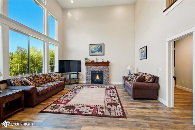 2034 E Sage Rd, Wasilla, AK 99654 - living room featuring a high ceiling, wood finished floors, baseboards, a stone fireplace, and recessed lighting