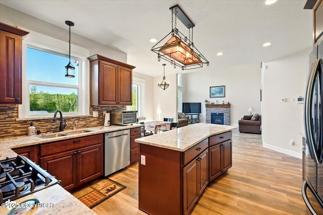 2034 E Sage Rd, Wasilla, AK 99654 - kitchen with appliances with stainless steel finishes, a sink, decorative backsplash, a fireplace, and a center island