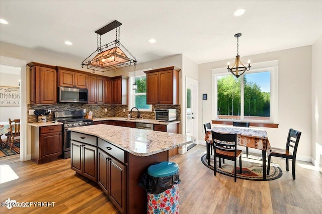 2034 E Sage Rd, Wasilla, AK 99654 - kitchen with appliances with stainless steel finishes, a chandelier, a sink, tasteful backsplash, and light wood-style floors