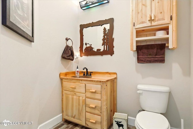 2034 E Sage Rd, Wasilla, AK 99654 - bathroom with baseboards, vanity, toilet, and wood finished floors