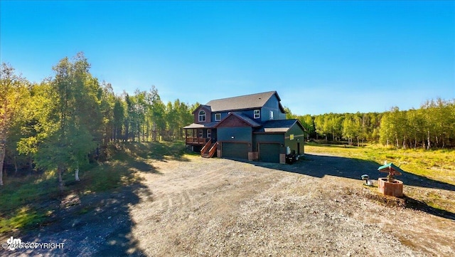 2034 E Sage Rd, Wasilla, AK 99654 - rustic home featuring driveway, a deck, an attached garage, and a forest view