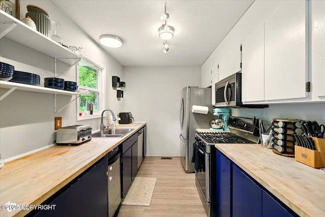 751 W Crestwood Ave, Wasilla, AK 99654 - kitchen with appliances with stainless steel finishes, a sink, light wood-style flooring, blue cabinetry, and butcher block counters
