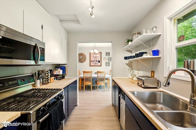 751 W Crestwood Ave, Wasilla, AK 99654 - kitchen with stainless steel appliances, a sink, white cabinetry, light countertops, and light wood-style flooring