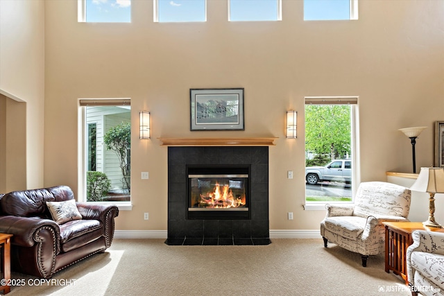 2931 Captain Cook Estates Cir, Anchorage, AK 99517 - carpeted living room featuring a towering ceiling, a tiled fireplace, and baseboards