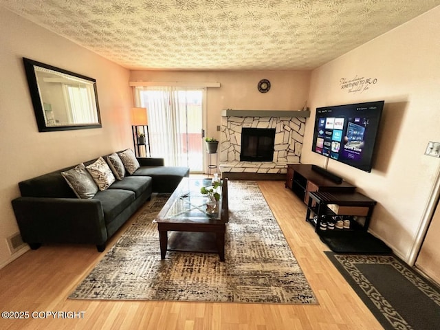 10250 Jamestown Dr # B-09, Anchorage, AK 99507 - living room with wood finished floors, a stone fireplace, a textured ceiling, and baseboards