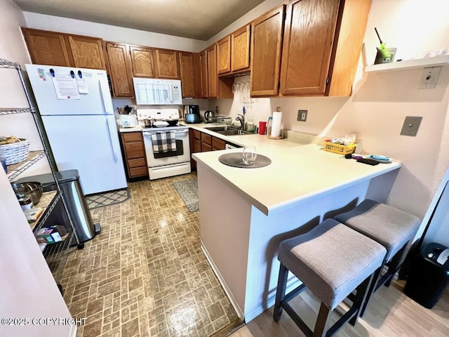 10250 Jamestown Dr # B-09, Anchorage, AK 99507 - kitchen with white appliances, a peninsula, light countertops, brown cabinets, and a breakfast bar area