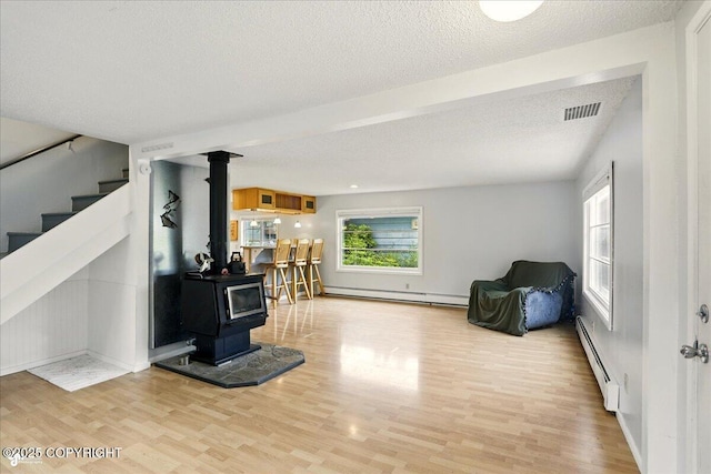 2527 Cottonwood St, Anchorage, AK 99508 - living area featuring a baseboard heating unit, a baseboard radiator, wood finished floors, a textured ceiling, and a wood stove
