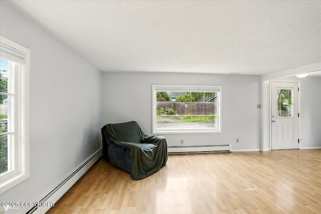 2527 Cottonwood St, Anchorage, AK 99508 - sitting room featuring a baseboard heating unit, healthy amount of natural light, light wood-style floors, and a textured ceiling