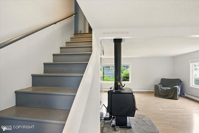 2527 Cottonwood St, Anchorage, AK 99508 - stairway featuring a textured ceiling, wood finished floors, baseboard heating, and a wood stove