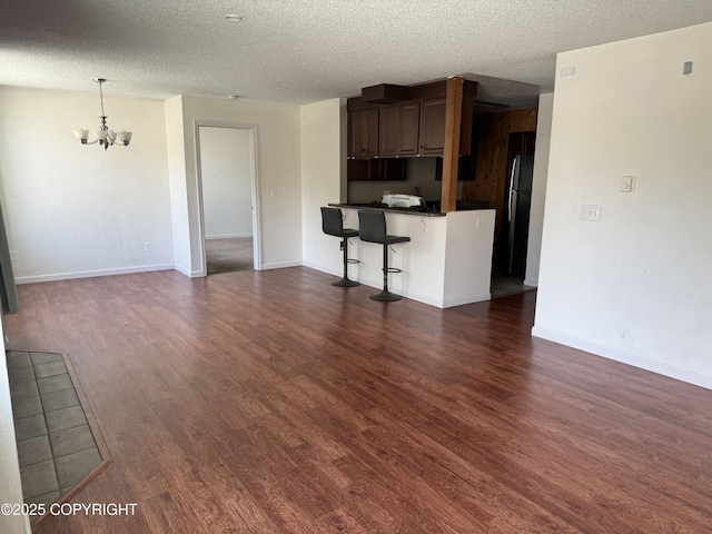 1008 Wildrose Ct, Anchorage, AK 99518 - kitchen with a chandelier, freestanding refrigerator, dark countertops, dark wood finished floors, and a breakfast bar