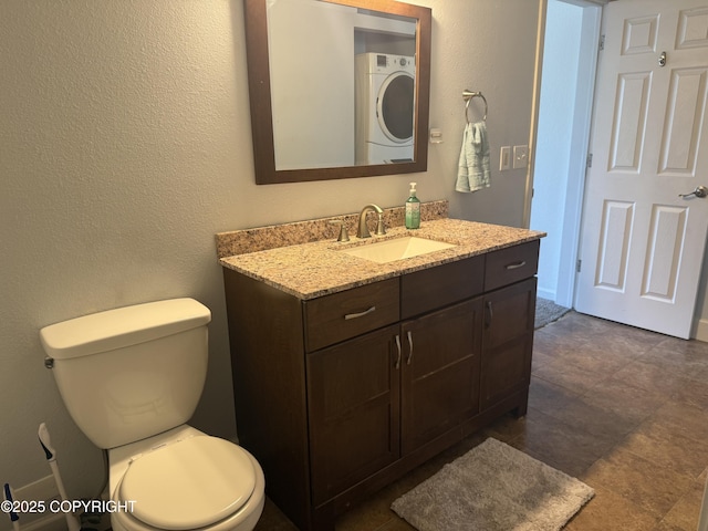 1008 Wildrose Ct, Anchorage, AK 99518 - bathroom featuring stacked washer / drying machine, vanity, toilet, and a textured wall