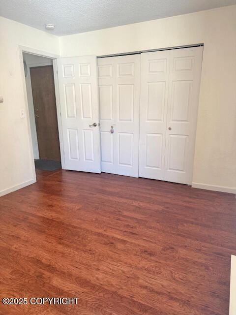 1008 Wildrose Ct, Anchorage, AK 99518 - unfurnished bedroom featuring baseboards, dark wood-style floors, a closet, and a textured ceiling